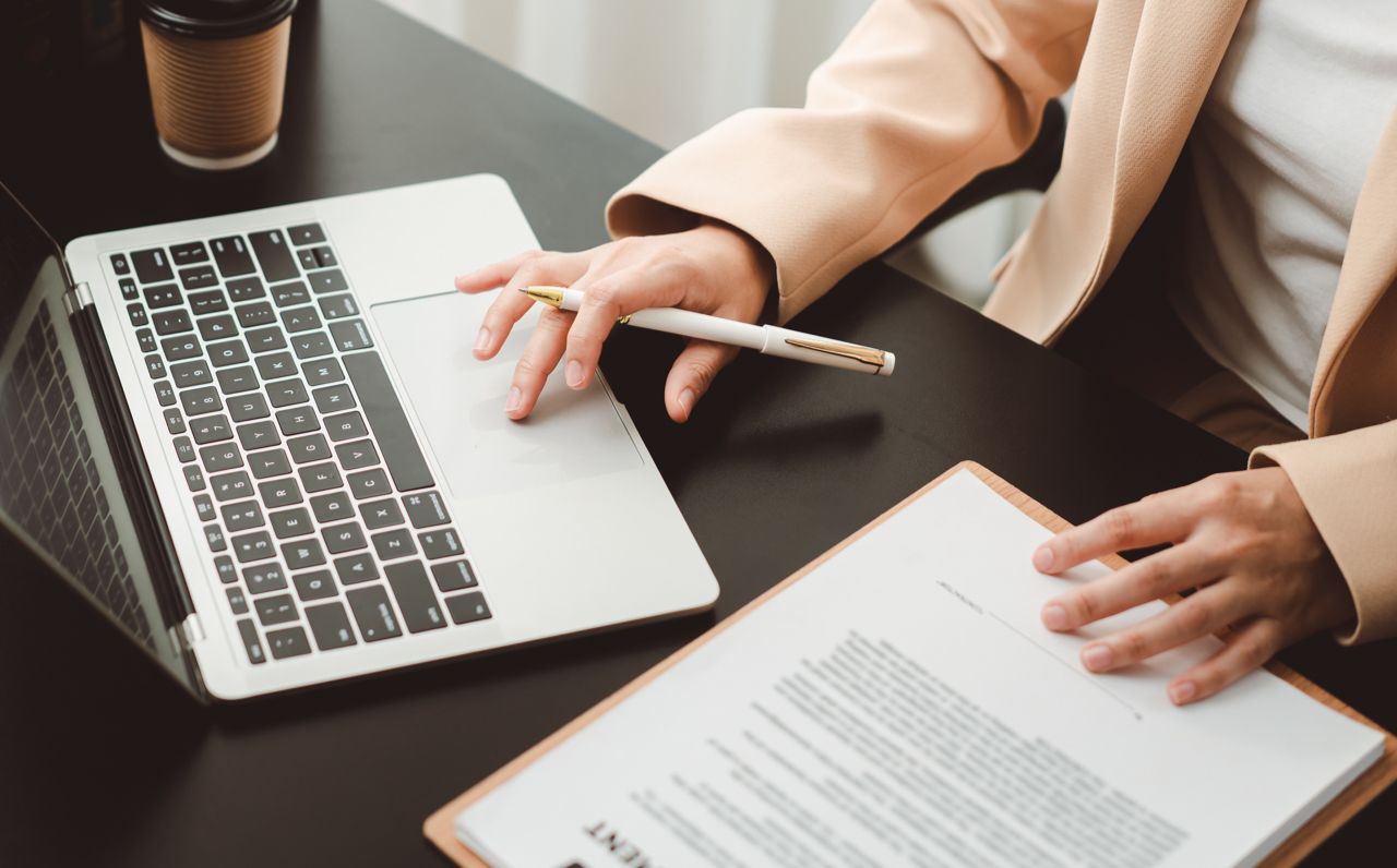 Woman at desk with paperwork, laptop, and coffee Woman at desk with paperwork, laptop, and coffee