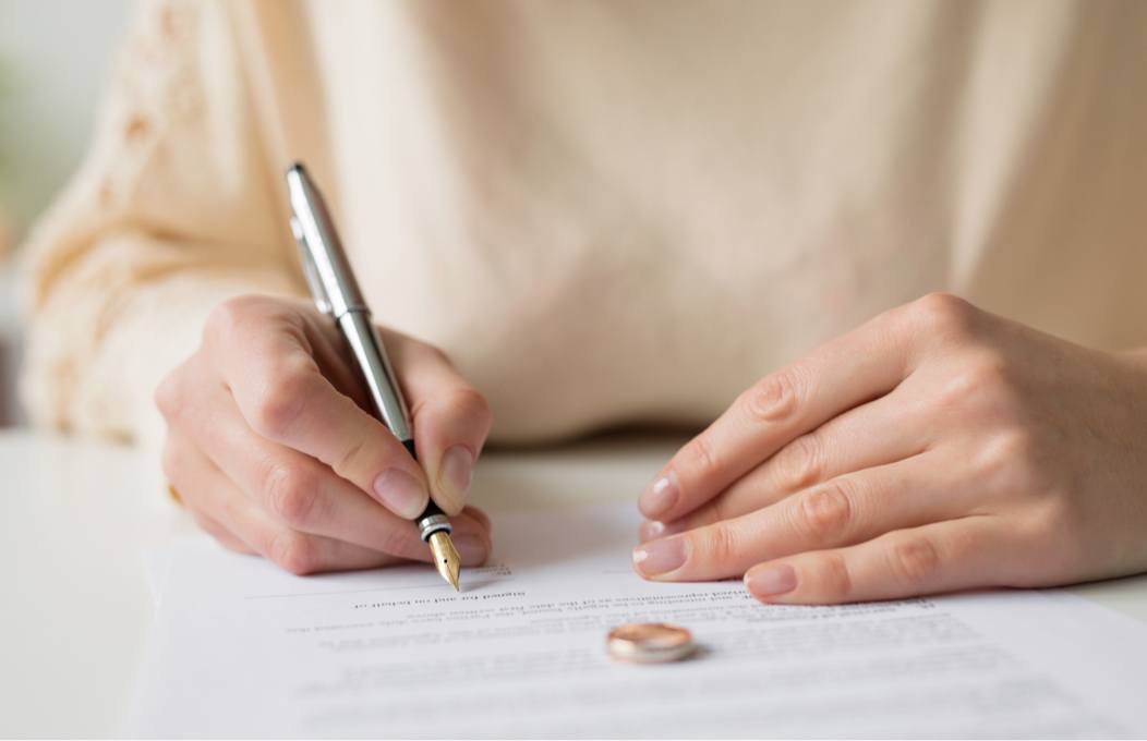 Woman Signing Divorce Document with Ring on Paper